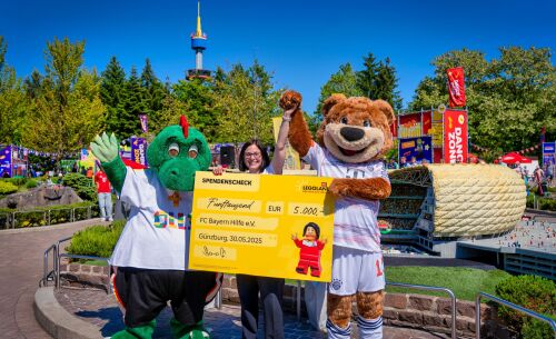 Manuela Stone, Geschäftsführerin des LEGOLAND Deutschland Resorts, übergab gemeinsam mit Parkmaskottchen Drache Olli nach der Enthüllung der Allianz Arena im MINILAND einen Spendenscheck über 5.000 Euro an Berni als Repräsentanten des FC Bayern München. 